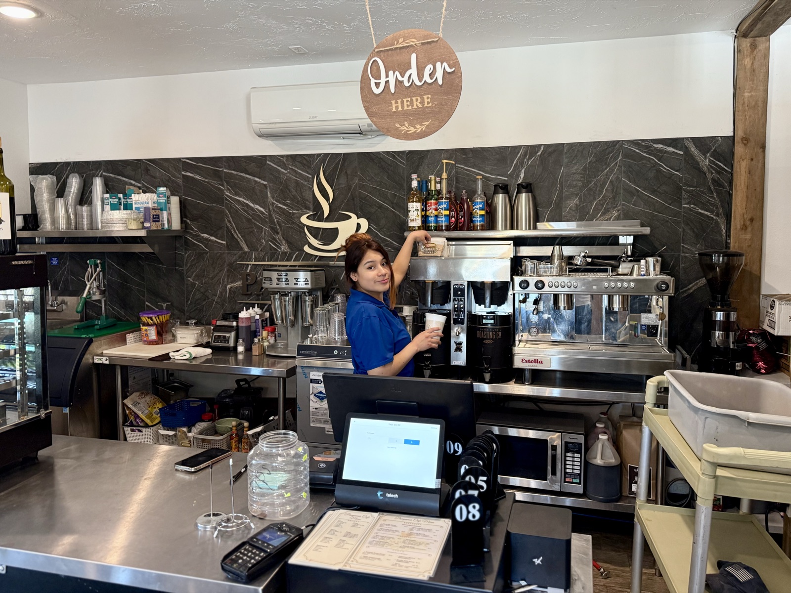 The barista at Pampano's espresso bar, Order Here sign above